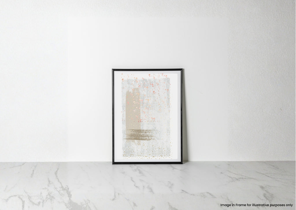 A framed abstract art print with soft beige, white, and gray brushstrokes and subtle pink speckles, displayed in a black frame leaning against a white wall on a light marble surface.
