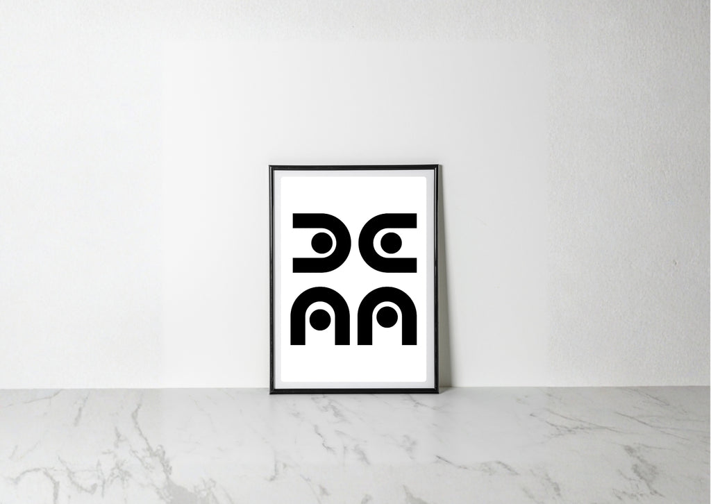A minimalist black and white art print with a thin black frame, leaning against a white wall on a light gray marble surface.