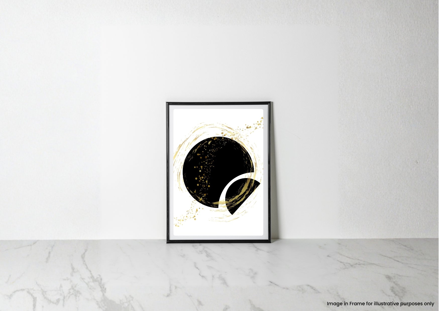 A framed abstract art print featuring a black circle with gold glitter-like speckles and gold circular brushstrokes on a white background, leaning against a white wall on a light marble surface.