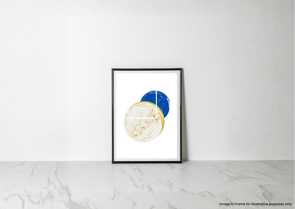 A minimalist framed art print featuring overlapping gold and blue circular abstract designs on a white background, leaning against a white wall on a light marble surface.