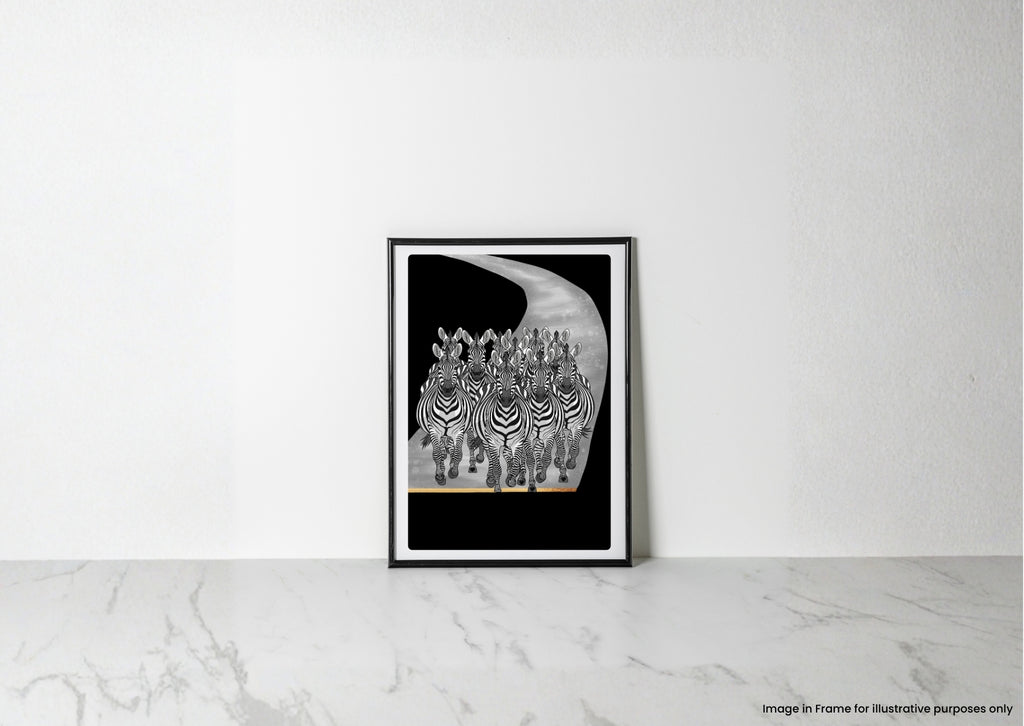 A framed black and white art print of zebras on a curved road, leaning against a white wall on a light marble surface.