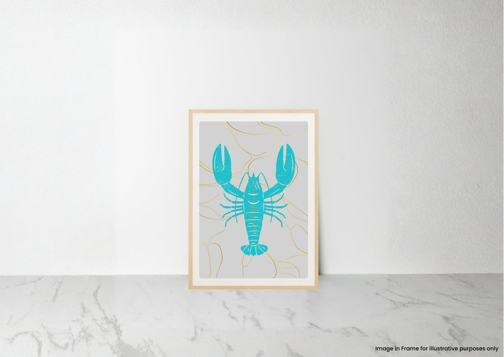 A framed art print featuring a turquoise lobster on a light gray background with thin gold line details, leaning against a white wall on a marble surface.