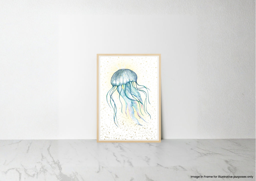 A vertical framed art print featuring a watercolor illustration of a blue and teal jellyfish on a white background with subtle gold speckles, leaning against a white wall on a light gray marble surface.