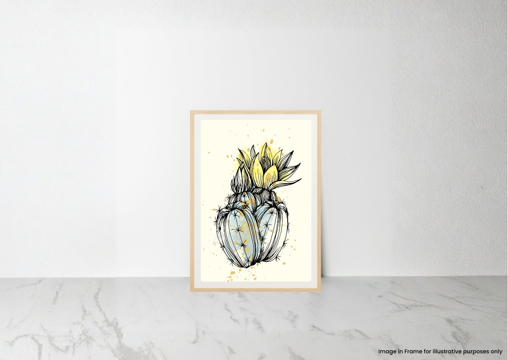 A framed art print featuring a stylized illustration of a cactus with yellow flowers, leaning against a white wall on a light marble surface.