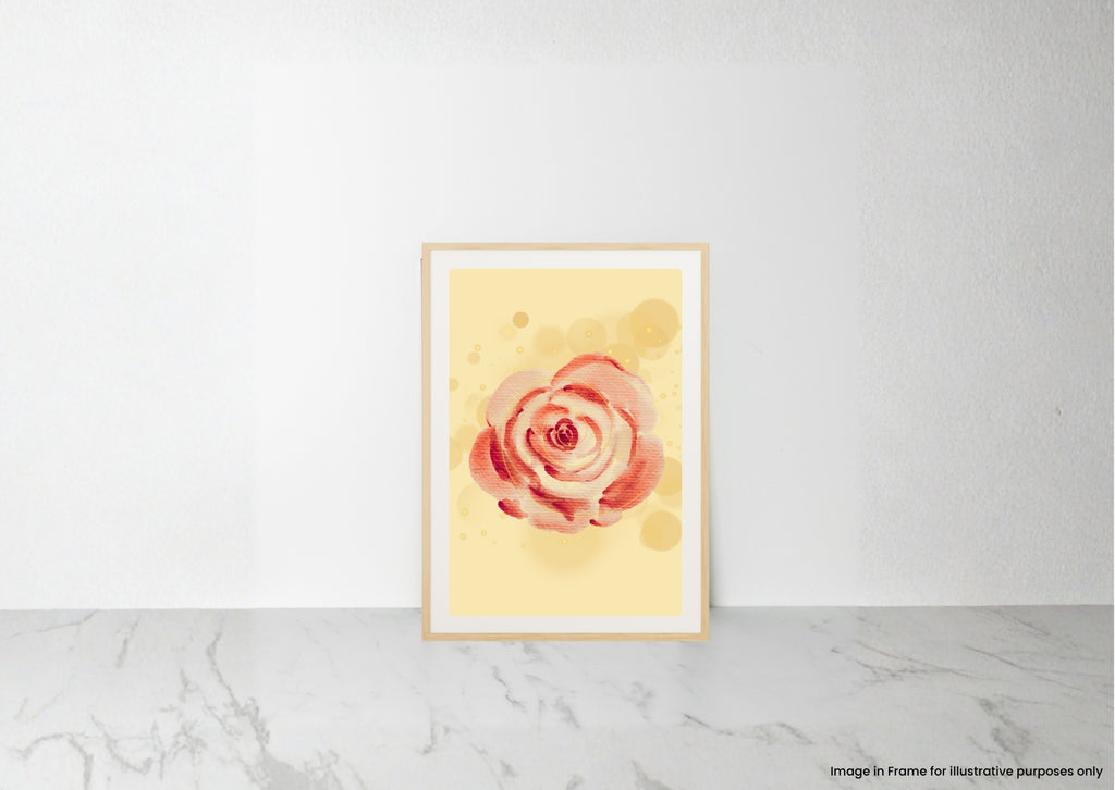 A vertical watercolor art print of a pink and red rose on a pale yellow background, displayed in a light wood frame leaning against a white wall on a marble surface.