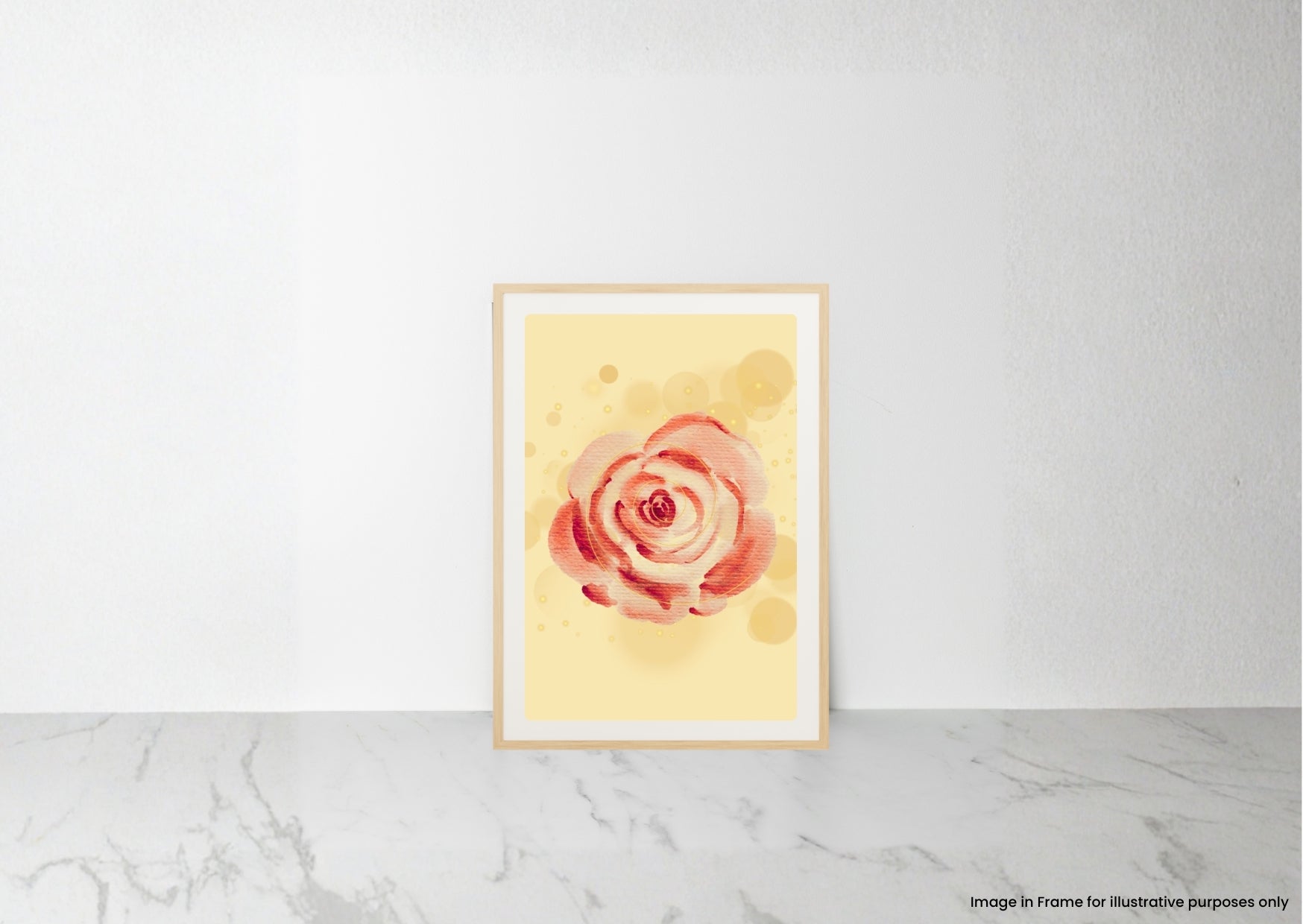 A vertical watercolor art print of a pink and red rose on a pale yellow background, displayed in a light wood frame leaning against a white wall on a marble surface.