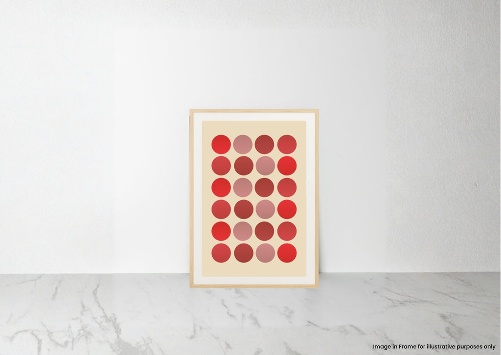 A framed art print featuring a grid of red, pink, and red gradient circles on a cream background, leaning against a white wall on a light gray marble surface.