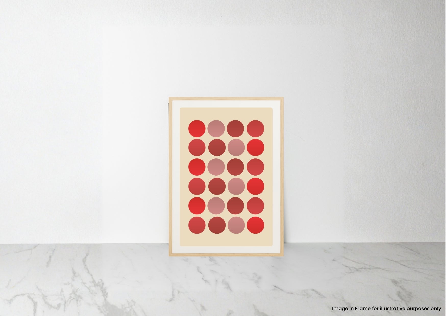 A framed art print featuring a grid of red, pink, and red gradient circles on a cream background, leaning against a white wall on a light gray marble surface.