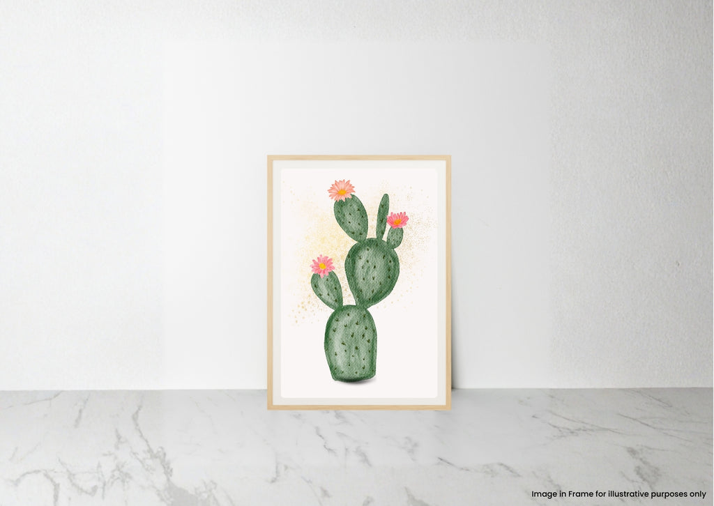 A framed art print featuring a watercolor illustration of a green prickly pear cactus with small pink flowers, leaning against a white wall on a light gray marble surface.