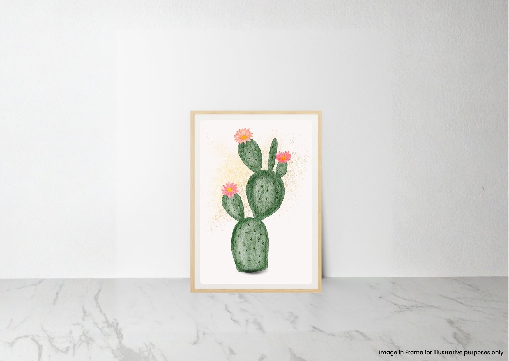A framed art print featuring a watercolor illustration of a green prickly pear cactus with small pink flowers, leaning against a white wall on a light gray marble surface.