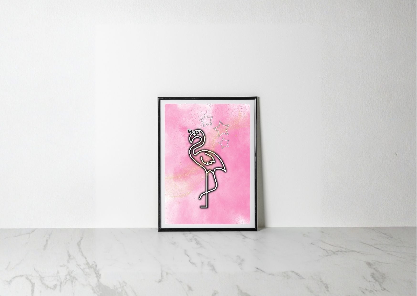 A framed art print featuring a minimalist black line drawing of a flamingo on a pink watercolor background, leaning against a white wall on a light marble surface.