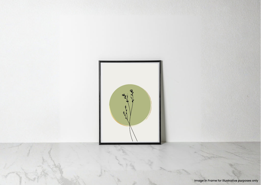 A minimalist framed art print featuring a sage green circle and delicate black botanical stems on a white background, displayed in a black frame leaning against a white wall on a light marble surface.