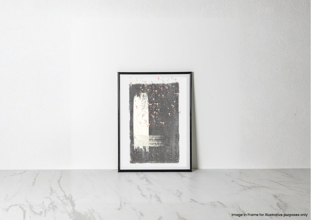 A framed abstract art print with a black and white design and small pink speckles, leaning against a white wall on a light marble surface.