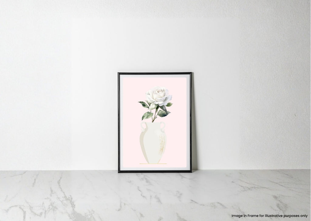 A framed botanical art print of a white rose in a cream vase against a pale pink background, leaning against a white wall on a light marble surface.